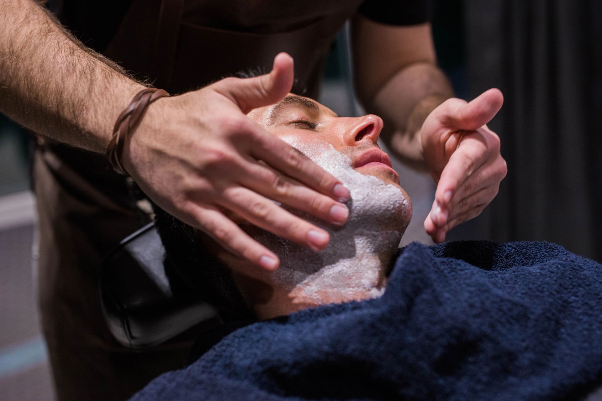 A barber giving a client a hot towel shave at Hubbard Clothing Co.
