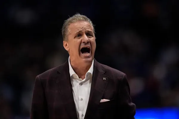 Basketball coach in a dark sport coat shouting from the sideline
