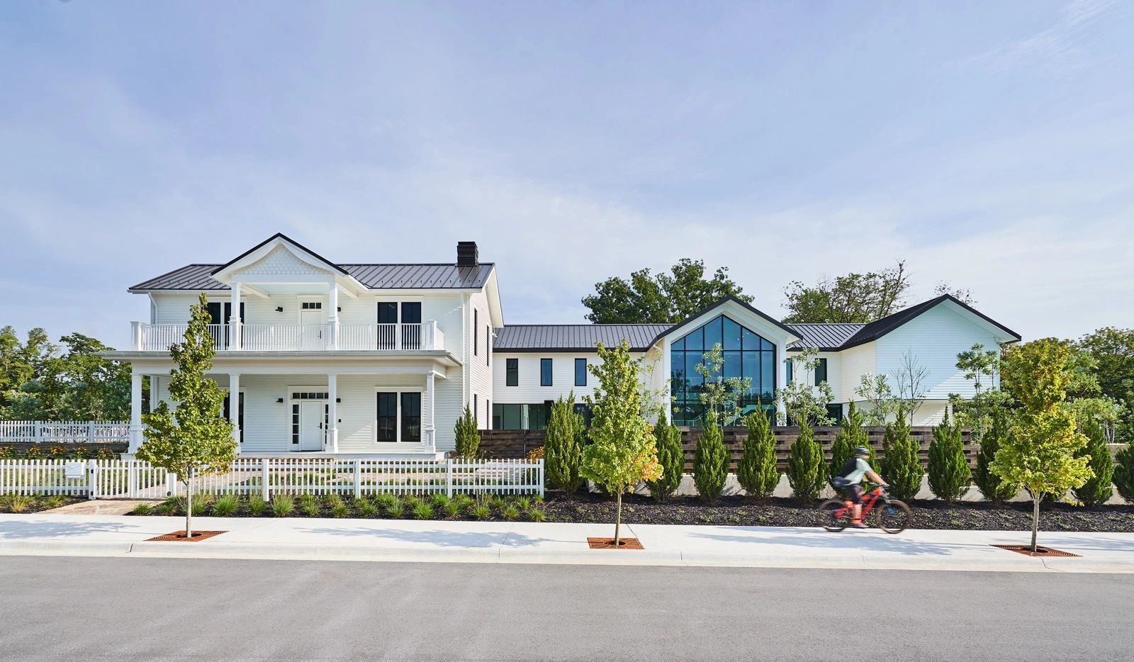 Modern white house with large windows and a picket fence.