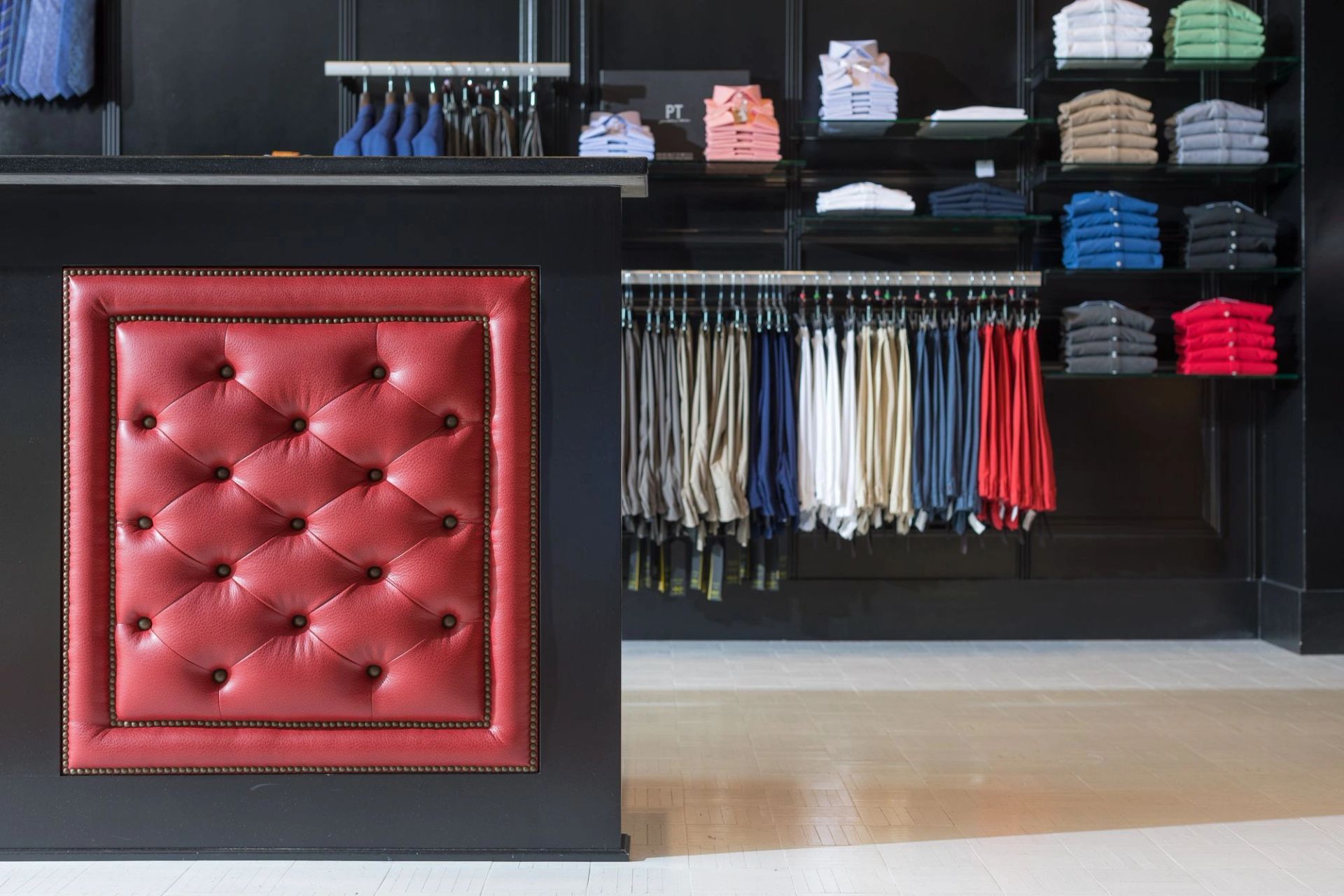 Hubbard Clothing Co. sales floor with tufted red leather display and shelves of folded knitwear